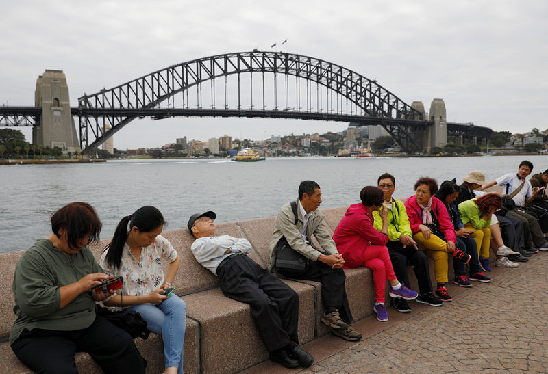 © Reuters. Chinese tourists rest near the Harbour Bridge in Sydney