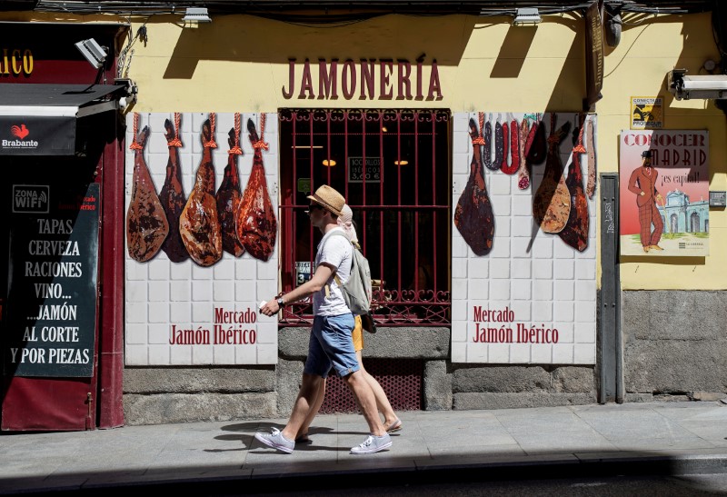 © Reuters. FILE PHOTO: Tourists walk past a Spanish Iberico ham shop in Madrid