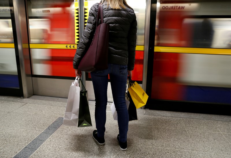 © Reuters. FILE PHOTO: A woman carries her shopping bags before boarding a train on the London Underground at Waterloo Station in London