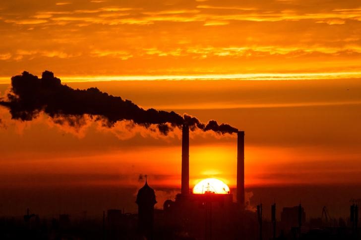 © Reuters. FILE PHOTO: Sun rises behind billowing chimneys of power station in Berlin