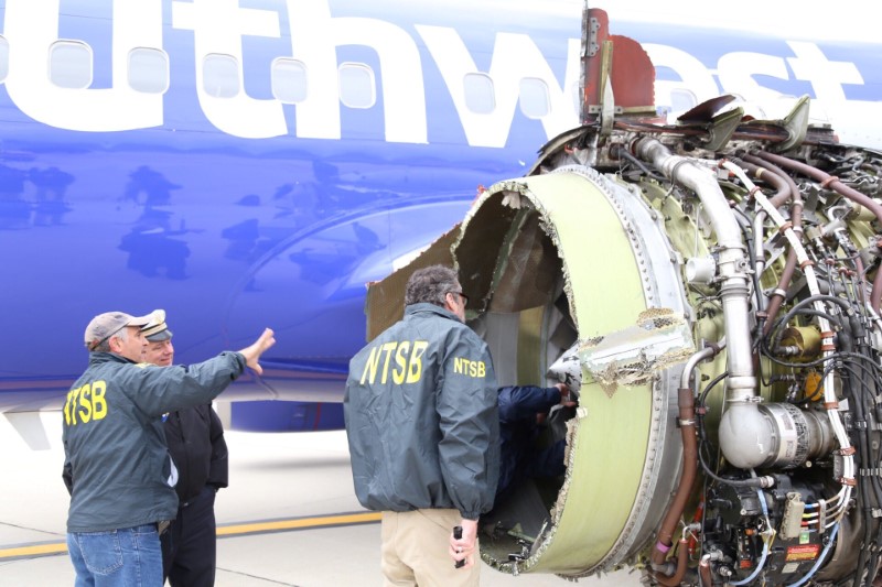 © Reuters. NTSB investigators on scene examining damage to the engine of the Southwest Airlines plane in Philadelphia