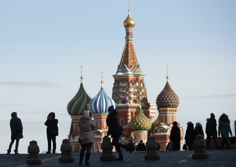 © Reuters. People take pictures next to St. Basil's Cathedral at Red Square in Moscow