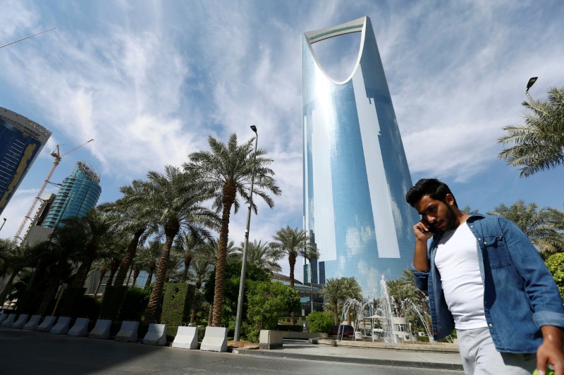 © Reuters. A man speaks on the phone as he walks past the Kingdom Centre Tower in Riyadh