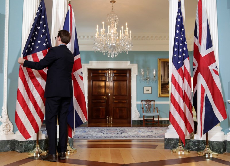 © Reuters. A State Department employee adjusts flags before a cancelled bi-lateral photo between U.S. Secretary of State Rex Tillerson and British Foreign Minister Boris Johnson at the State Department in Washington