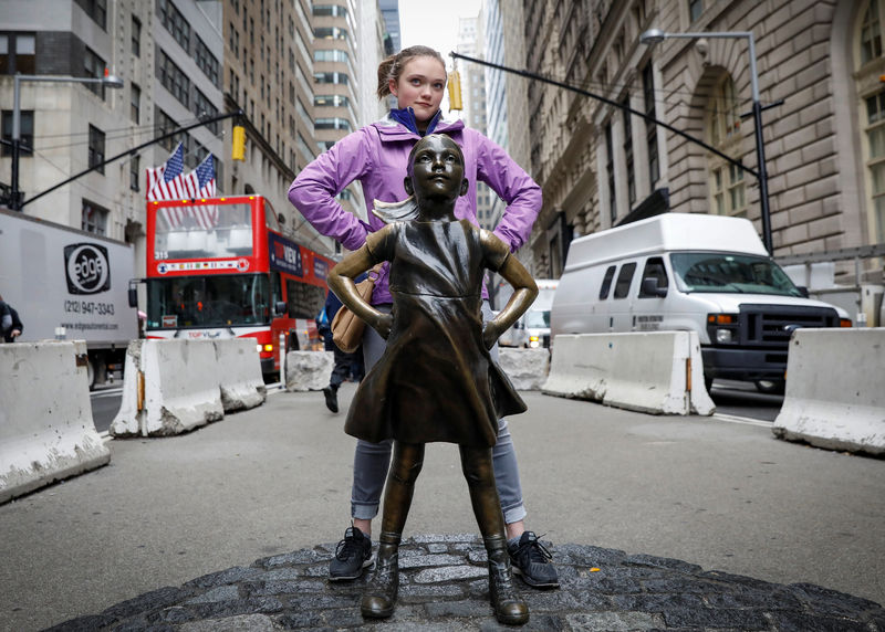 © Reuters. A girl poses with the 'Fearless Girl' statue on Broadway in the Financial District of Manhattan in New York City