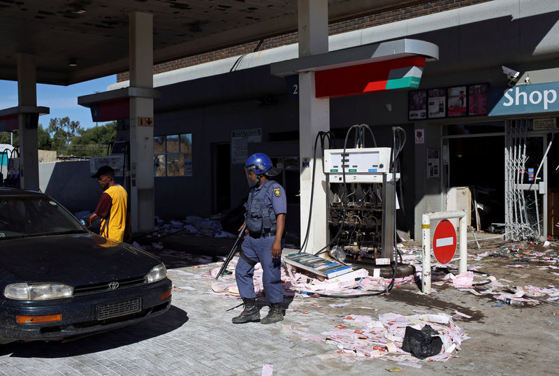 © Reuters. A Police officer stands guard after a filling station was looted by protesters in Mahikeng