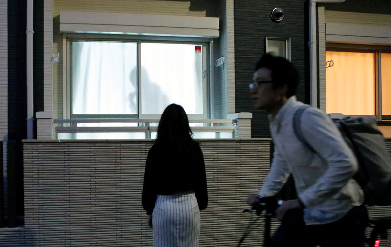 © Reuters. Leopalace 21 Corp employee, Mai Shibata, poses in front of a window, on which the company's security system 'Man on the Curtain' projects a man's shadow, in Tokyo