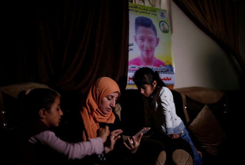 © Reuters. Mother of Palestinian boy who was shot dead by Israeli troops during clashes at the Israel-Gaza border looks at her son's photos at her house, in Gaza Strip