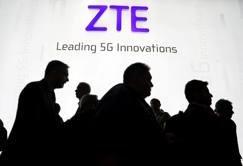 © Reuters. FILE PHOTO - Visitors pass in front of the ZTE booth at the Mobile World Congress in Barcelona