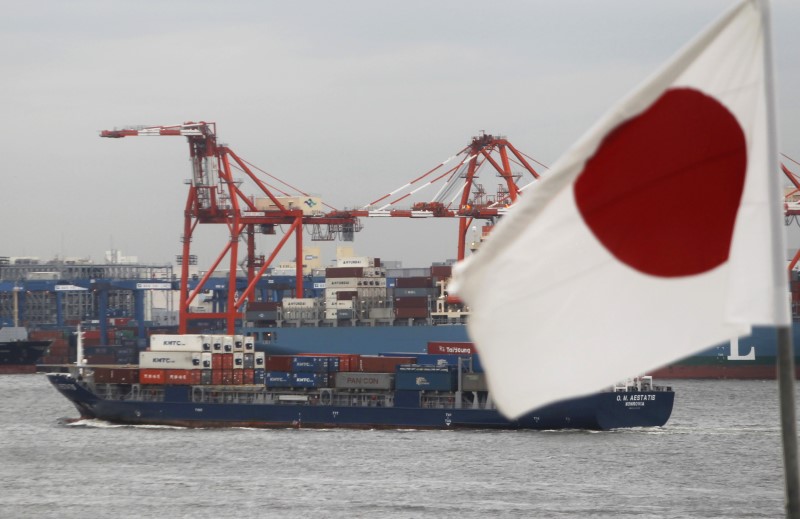 © Reuters. A Japanese flag is seen in front of a cargo ship carrying containers at a port in Tokyo