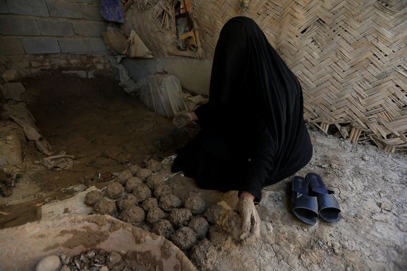 © Reuters. A woman makes ''turba'', a piece of stone or molded clay made of local soil, at her home in Kerbala