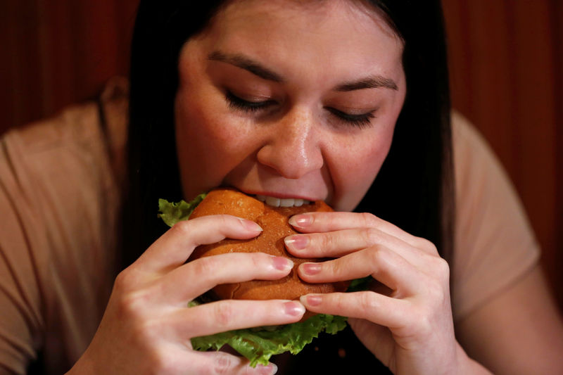 © Reuters. Kristin Barnaby eats a burger prepared with a tarantula at Bull City Burger and Brewery in celebration of Exotic Meat Month in Durham, North Carolina