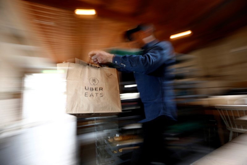 © Reuters. A bag of donuts destined for delivery via Uber Eats is rushed to a driver from a kitchen in Sydney