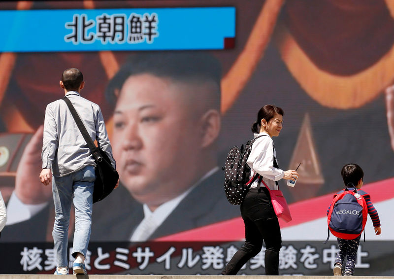 © Reuters. People walk past a street monitor showing North Korea's leader Kim Jong Un in a news report about North Korea's announcement, in Tokyo