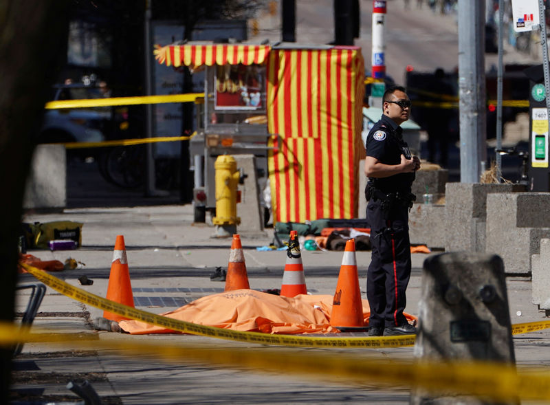 © Reuters. Policial ao lado de vítima no local em que van atingiu pedestres em Toronto, Canadá