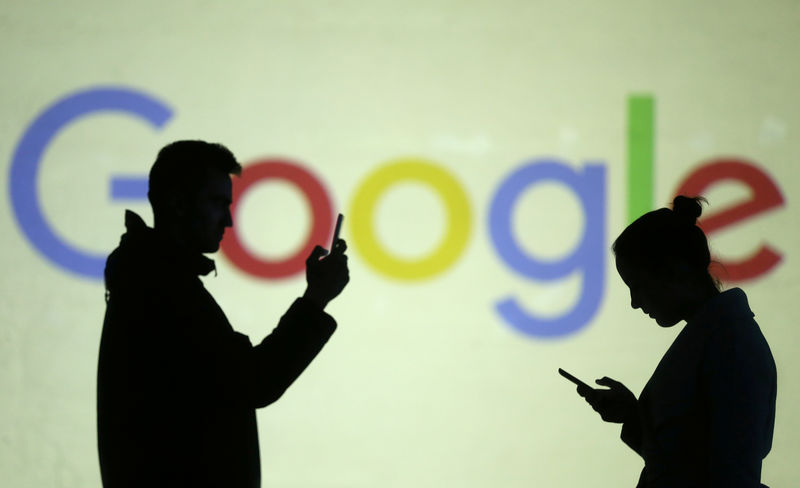 © Reuters. Silhouettes of mobile users are seen next to a screen projection of Google logo in this picture illustration