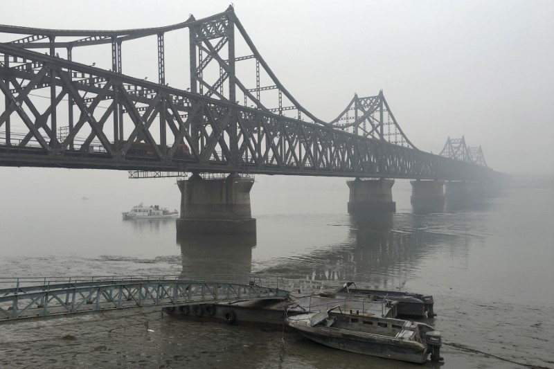 © Reuters. Trucks move across the bridge linking North Korea with the Chinese border city of Dandong