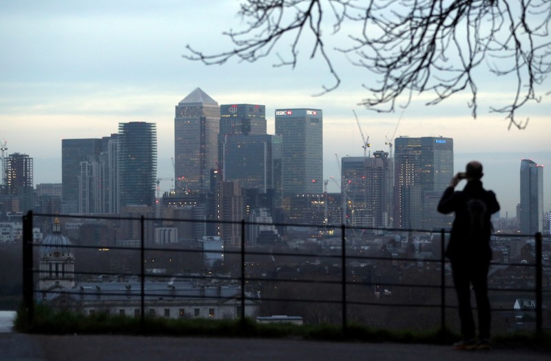 © Reuters. FILE PHOTO: A man takes a photograph of the Canary Wharf financial district from Greenwich Park in London