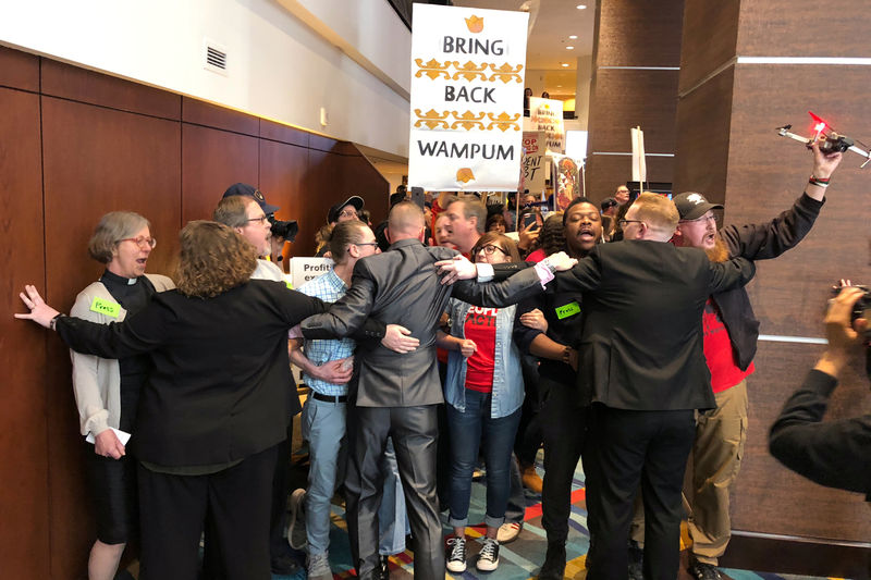 © Reuters. Guards hold back about 100 protestors gathered in a hotel lobby outside Wells Fargo & Co’s annual shareholder meeting in Des Moines