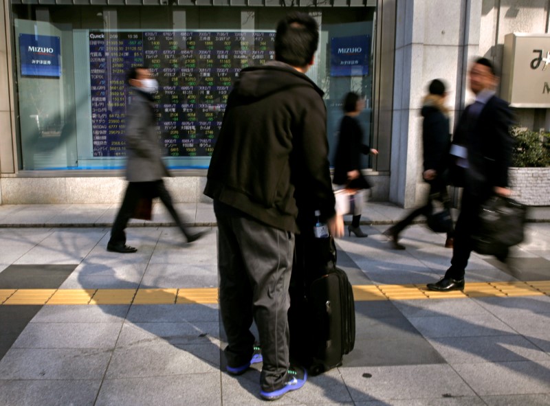 © Reuters. FILE PHOTO: A man looks at an electronic stock quotation board outside a brokerage in Tokyo
