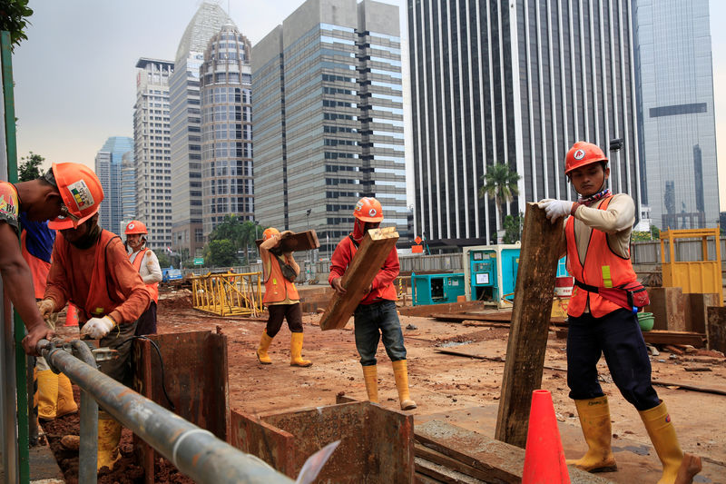 © Reuters. Workers carry pieces of wood as walks at the Jakarta Mass Rapid Transit construction at Sudirman Business District in Jakarta