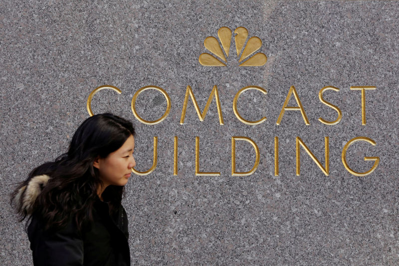 © Reuters. FILE PHOTO: A woman walks past the NBC and Comcast logos on 30 Rockefeller Plaza in midtown Manhattan in New York
