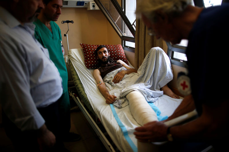 © Reuters. Wounded Palestinian is checked by British vascular surgeon John Wolfe, who was invited to Gaza by ICRC, in a hospital in Gaza City