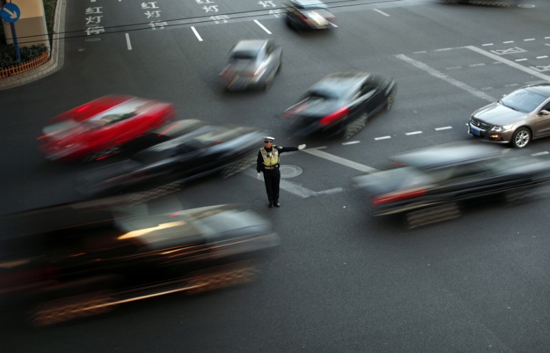 © Reuters. A policeman directs traffic at a busy street of downtown Shanghai