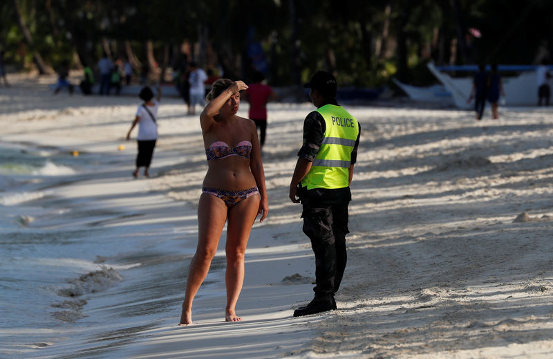 © Reuters. Policial pede que turista deixe praia das Filipinas durante interdição em Boracay