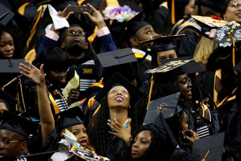 © Reuters. Graduates look at screen during a commencement for Medgar Evers College in New York City