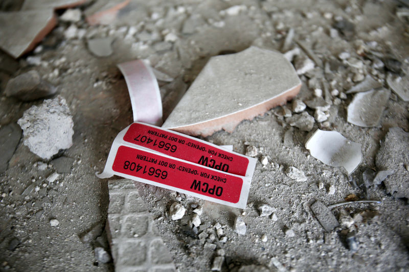© Reuters. Наклейки с пометкой ОЗХО в разрушенном доме в Думе