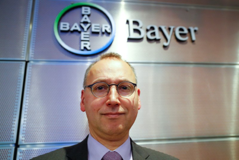 © Reuters. Bayer CEO Baumann is posing in front of the drugmaker's logo following the annual results news conference in Leverkusen