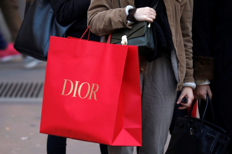 © Reuters. A shopper carries a Dior shopping bag as she takes care of her last-minute Christmas holiday gift purchases in Paris