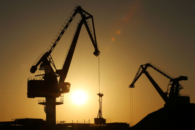 © Reuters. Cranes transporting imported sulphur are seen silhouetted at a port in Nantong