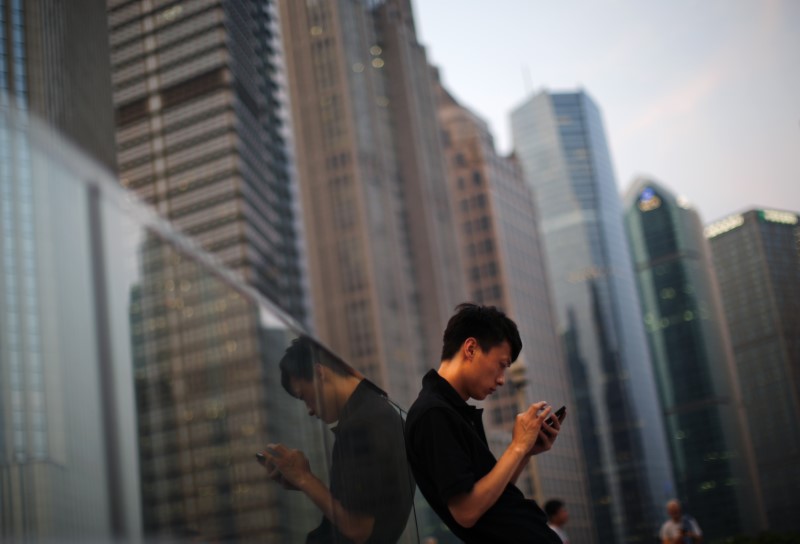 © Reuters. A man looks at the screen of his mobile phone  at Pudong financial district in Shanghai