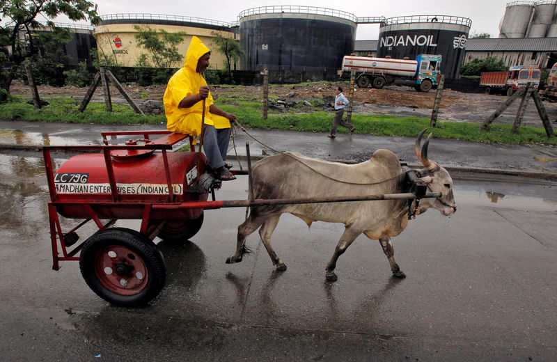 © Reuters. FILE PHOTO: A worker transporting kerosene in a bullock cart travels past Indian Oil Corporation's fuel depot in Mumbai