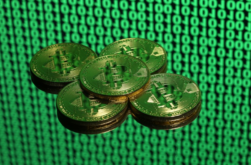 © Reuters. Bitcoin tokens are seen placed on a monitor that displays binary digits in this illustration picture