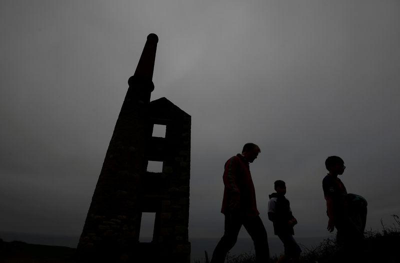 © Reuters. FILE PHOTO: A family walk past the remains of the engine house at the Wheal Prosper copper and tin mine near Porthleven in Cornwall