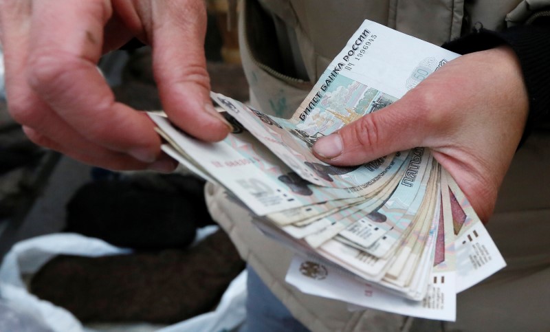 © Reuters. FILE PHOTO: Vendor counts Russian rouble banknotes at street market in Krasnoyarsk