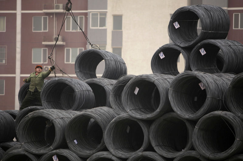 © Reuters. FILE PHOTO: A labourer works on coils of steel wire at a steel wholesale market in Beijing