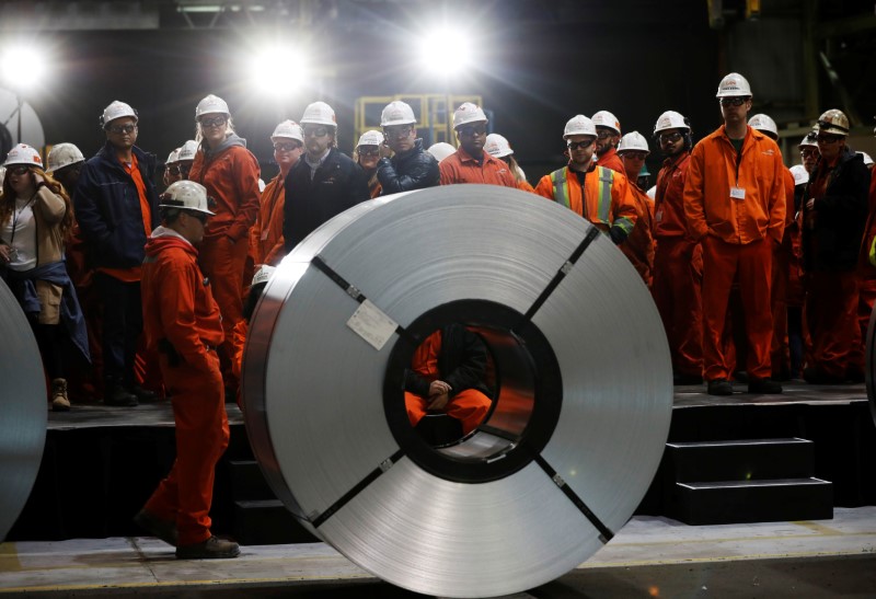 © Reuters. Workers stand behind rolls of steel at the ArcelorMittal Dofasco steel plant in Hamilton