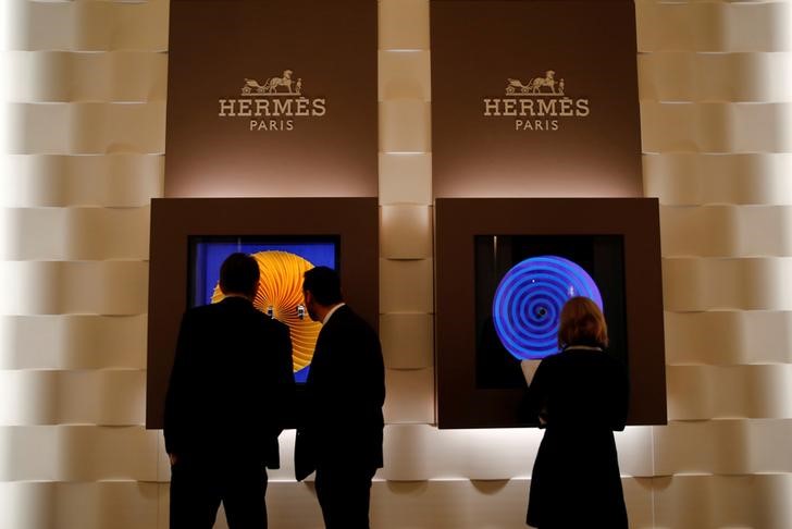 © Reuters. FILE PHOTO: Visitors look at Hermes watch models at the SIHH watch fair in Geneva