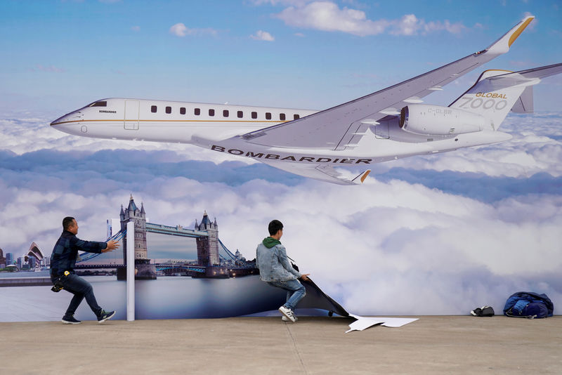 © Reuters. FILE PHOTO: Workers put up a billboard poster of the Bombardier Global 7000 aircraft at the Asian Business Aviation Conference and Exhibition at Hongqiao International Airport in Shanghai