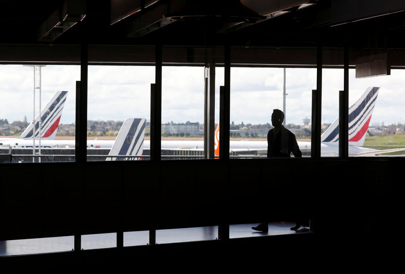 © Reuters. A passenger walks as Air France planes are parked on the tarmac at Orly Airport near Paris as Air France pilots, cabin and ground crews unions call for a strike over salaries