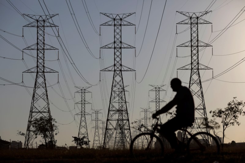 © Reuters. Homem passa de bicicleta em frente a torres de energia em Brasília, Brasil