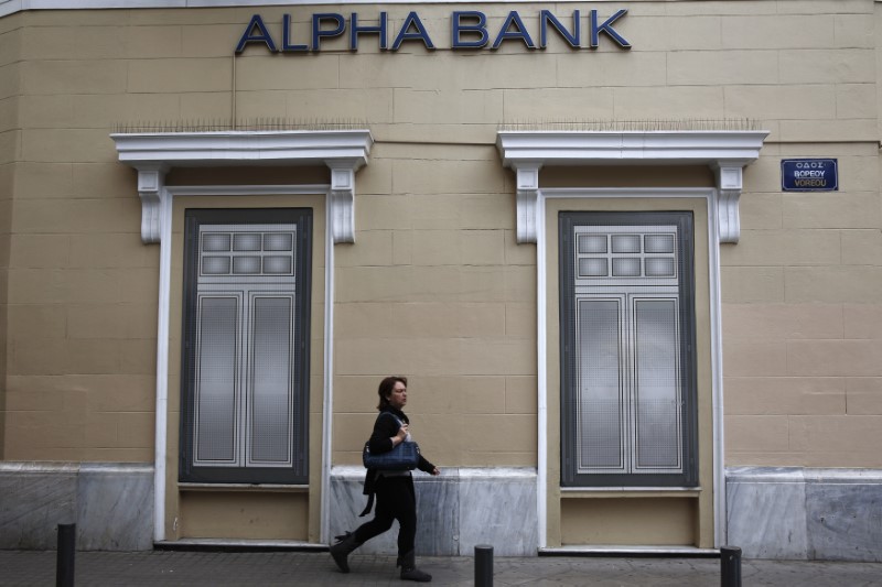 © Reuters. A woman makes her way past the logo of Alpha Bank in Athens