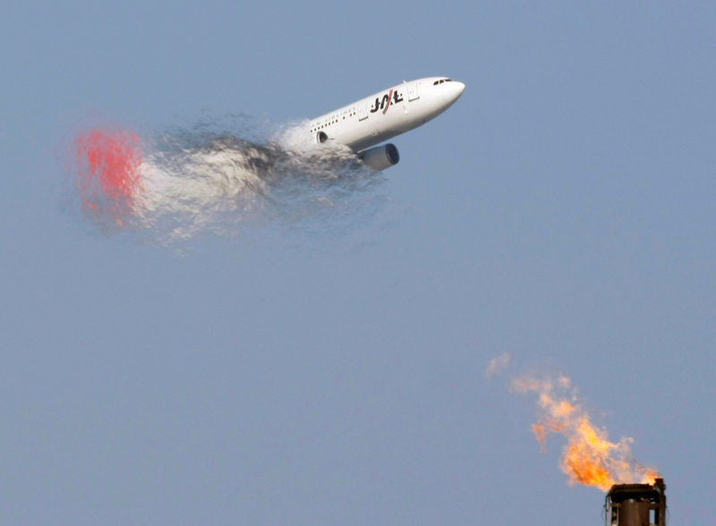 © Reuters. FILE PHOTO: A Japan Airlines airplane flies past a factory's chimney at an industrial district in Tokyo