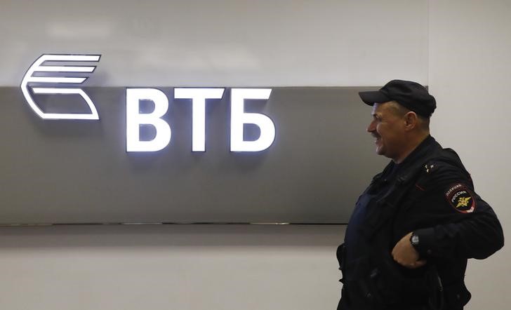 © Reuters. A police officer stands guard near a sign with the logo of the Russian lender VTB in Moscow