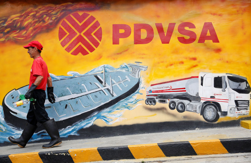 © Reuters. FILE PHOTO: A worker walks past a mural with a PDVSA logo at its gas station in Caracas