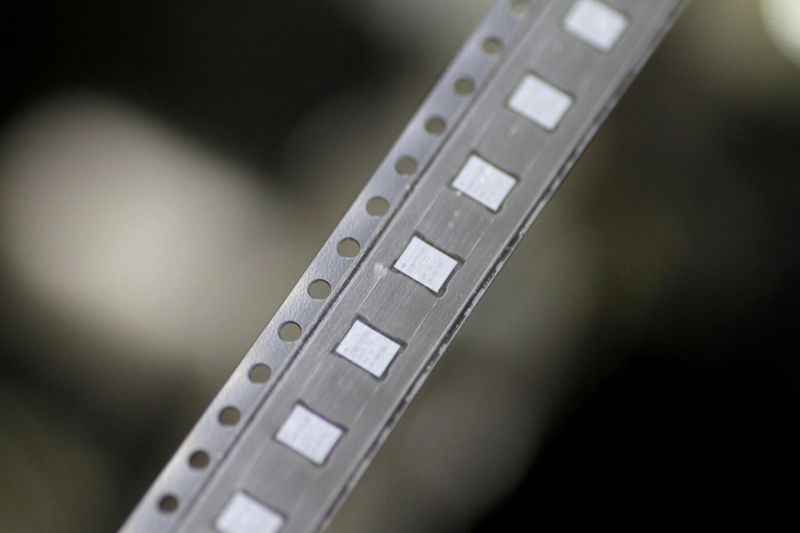 © Reuters. FILE PHOTO: Microchips emerge from a machine onto a roll in the clean room at the UTAC plant in Singapore